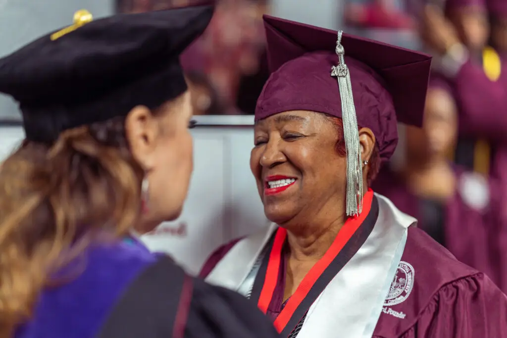 NCCU graduate smiling at faculty member during commencement